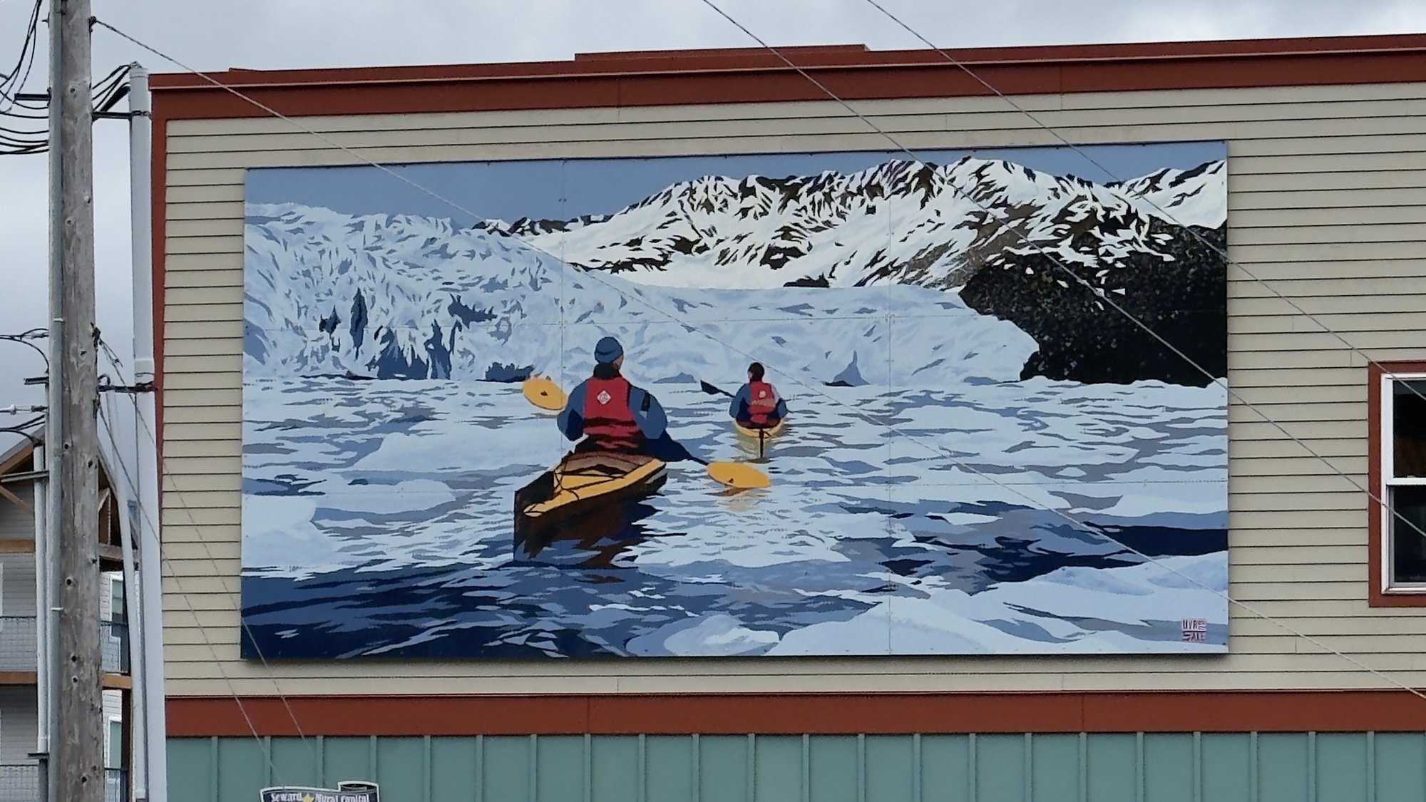 Mural of two kayakers paddling toward a glacier — seen on a wall in Alaska